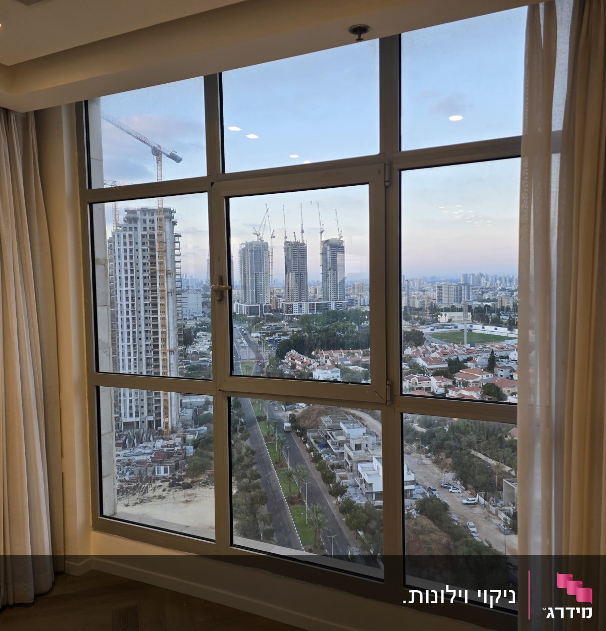 וילונות לבנים ליד חלון עם נוף עירוני